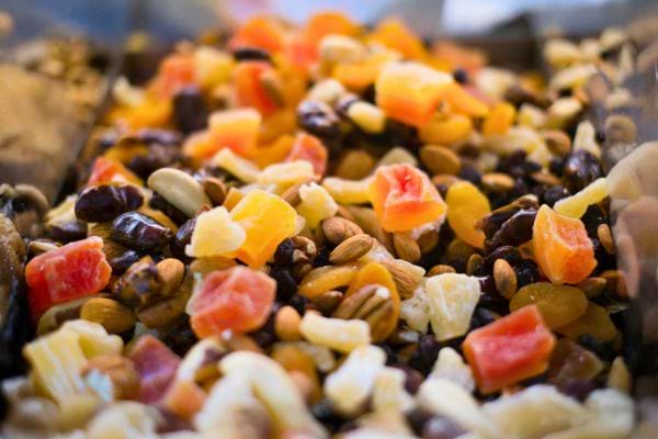 un gros plan montre un melange colore de fruits secs noix et graines