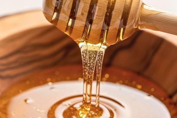 du miel dore coule dune cuillere en bois dans un recipient