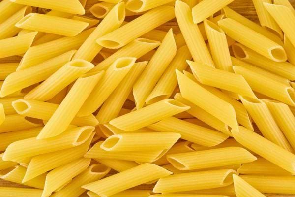 un gros plan de pates penne crues jaunes disposees en vrac