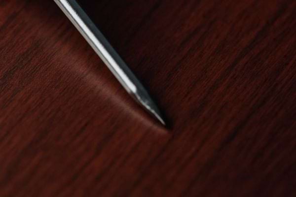 Pointe metallique posee sur une surface en bois fonce