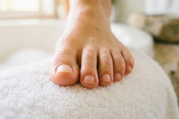 healthy toes resting on a pristine white fluffy towel in a bright, spa-like bathroom setting