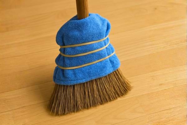 Des &eacute;lastiques en caoutchouc &eacute;pais fixant solidement un chiffon en microfibre bleu autour de la t&ecirc;te d'un balai-brosse