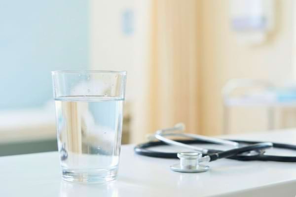 un verre d'eau pure et fra&icirc;che &agrave; c&ocirc;t&eacute; d'un st&eacute;thoscope flou en arri&egrave;re-plan