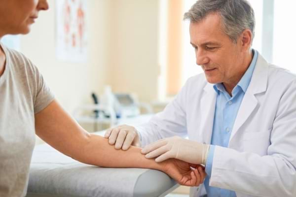un m&eacute;decin bienveillant en blouse blanche examinant doucement le bras d'un patient