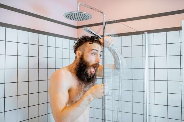 une personne sous la douche avec une expression de surprise totale face &agrave; un jet d'eau soudainement glac&eacute;