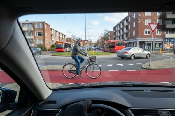 Close up shot from inside a car looking out the windshield, stopped at a yield line of a roundabout
