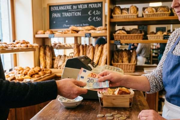une personne payant avec des billets en euros dans une boulangerie