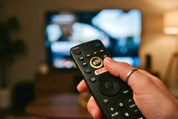 une personne tenant une t&eacute;l&eacute;commande de t&eacute;l&eacute;vision moderne