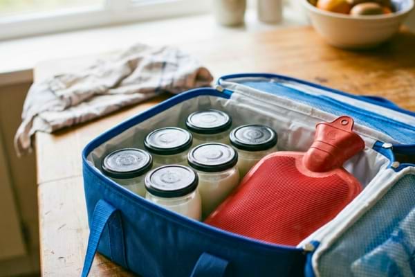 une glacière de pique-nique bleue ouverte, à l'intérieur se trouvent des pots en verre