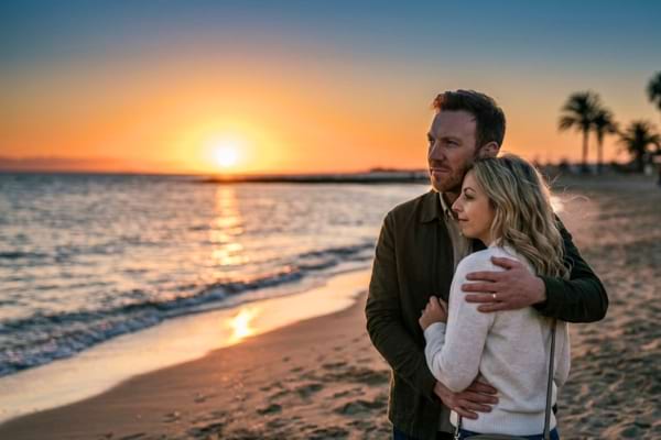 Un couple avec une diff&eacute;rence d'&acirc;ge (homme 40 ans, femme 25 ans) regardant un coucher de soleil 