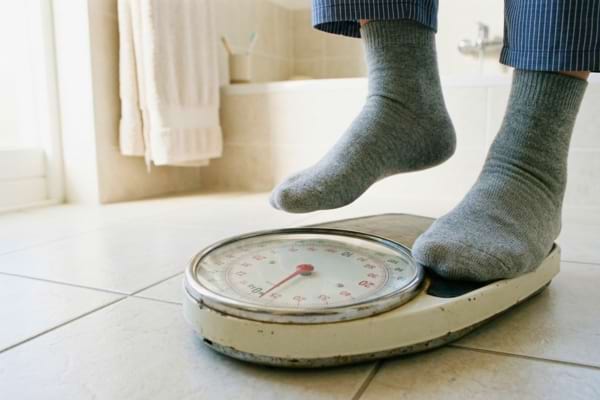 Un p&egrave;se-personne m&eacute;canique de style r&eacute;tro pos&eacute; sur le carrelage clair d'une salle de bain