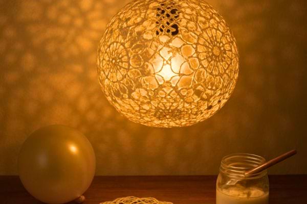 une lampe ronde en dentelle projette une lumiere douce dans la piece