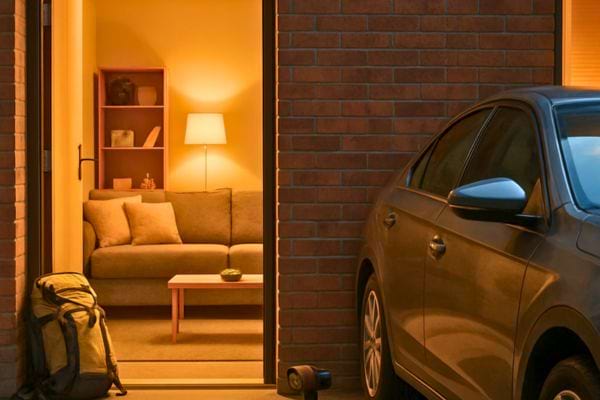 vue dune maison avec une voiture garee et un salon eclaire a linterieur