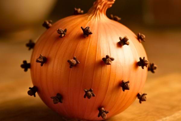 un oignon avec des clous de girofle pose sur une table en bois