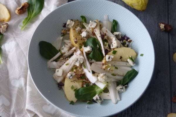 une salade d'endives roquefort et poire dans une assiette creuse blanche et bleue