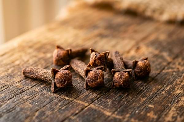 clous de girofle entiers pos&eacute;s sur une table en bois rustique 