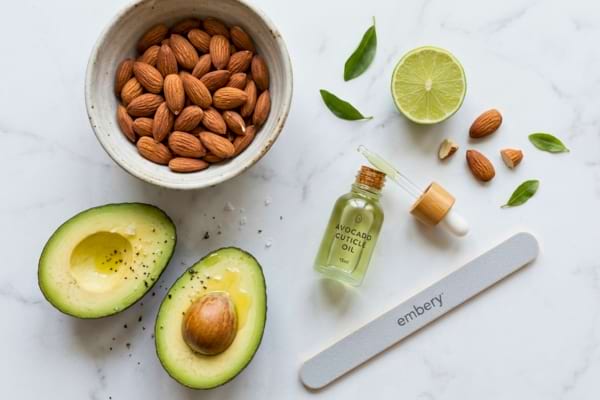 un bol d'amandes, un demi-avocat, une petite bouteille d'huile &agrave; cuticules