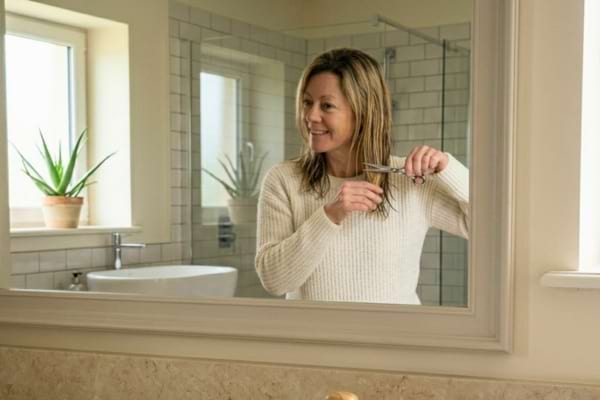 Une femme qui se coupe ses cheveux elle même pour faire des économies