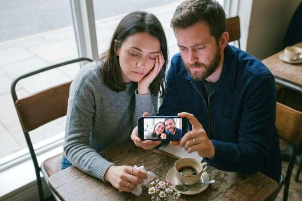 Un couple prend un selfie souriant avec un smartphone.