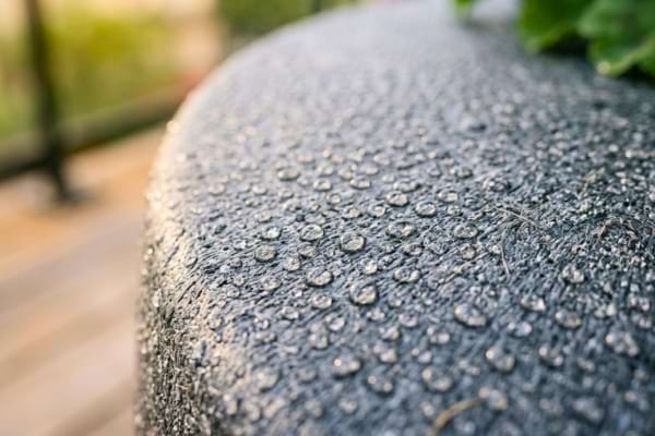 un pot en plastique recycl&eacute; de couleur anthracite. Des gouttes de ros&eacute;e perlent sur la surface