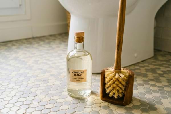 Bouteille en verre remplie de vinaigre blanc posée sur un sol en carrelage
