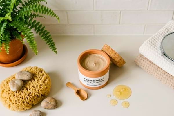 une éponge, un pot de pierre d'argile ouvert et quelques gouttes de liquide vaisselle