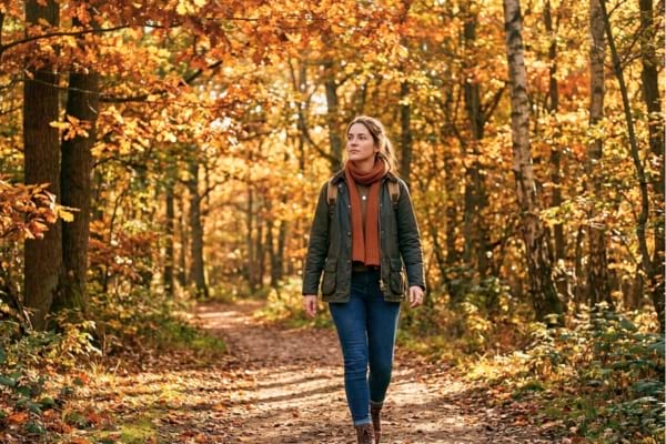 jeune femme marchant seule dans la for&ecirc;t d'automne, avec une lumi&egrave;re dor&eacute;e symbolisant la s&eacute;r&eacute;nit&eacute;