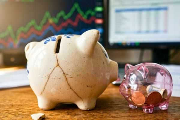 macro shot of a ceramic piggy bank with a small crack on it, sitting on a wooden desk