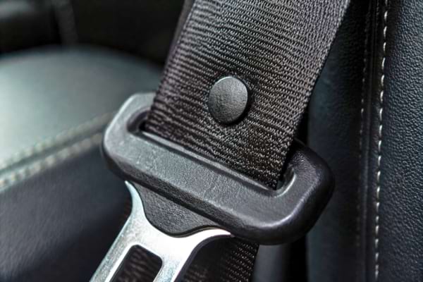 a car seatbelt showing the small round plastic stopper button holding the metal buckle in place