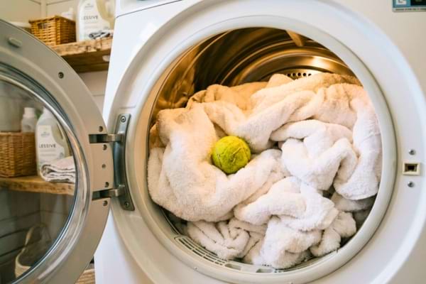un s&egrave;che-linge ouvert, montrant des serviettes de bain tr&egrave;s gonflantes avec une balle de tennis