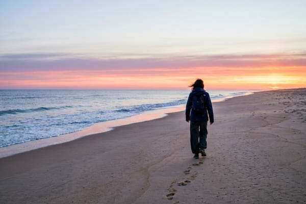 Une personne marchant seule sur une plage &agrave; l'aube