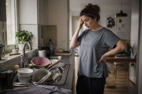 femme devant &eacute;vier avec vaisselle sale