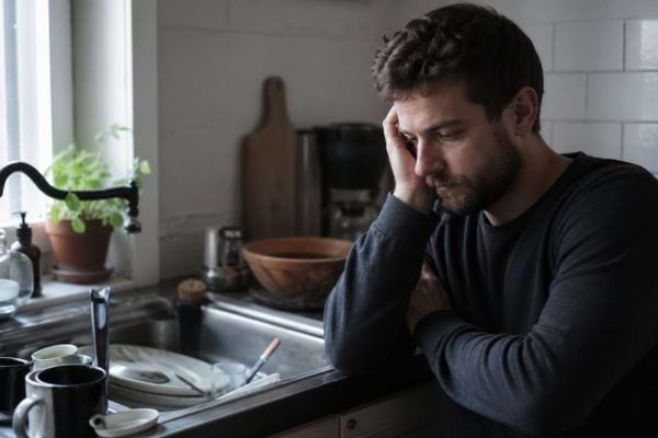 homme fatigu&eacute;e devant &eacute;vier avec vaisselle sale