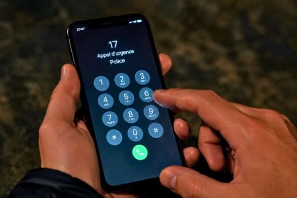 une personne tenant un smartphone, le doigt s'appr&ecirc;tant &agrave; composer le num&eacute;ro d'urgence de la police