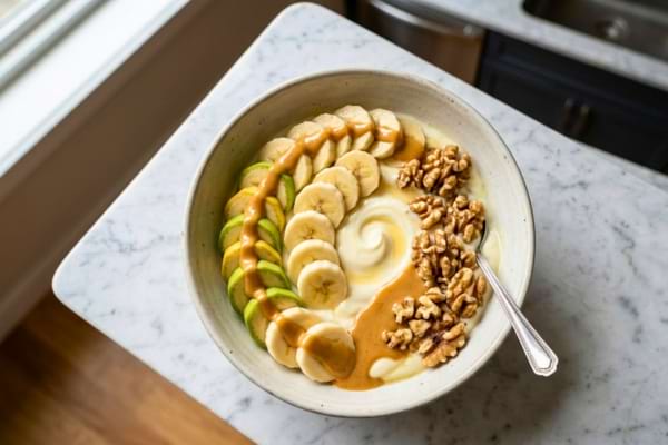 Un bol de petit-d&eacute;jeuner app&eacute;tissant vu de haut (flat lay). Le bol contient du yaourt grec onctueux, garni de rondelles de banane