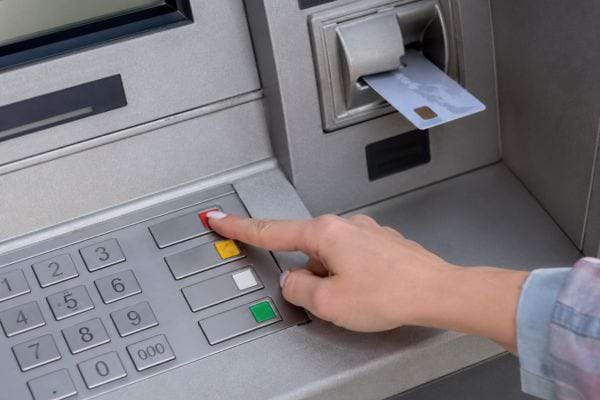 une femme appuie sur le bouton rouge du distributeur automatique de billets