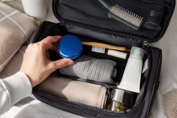 Trousse de toilette ouverte avec un petit pot bleu de cr&egrave;me hydratante 