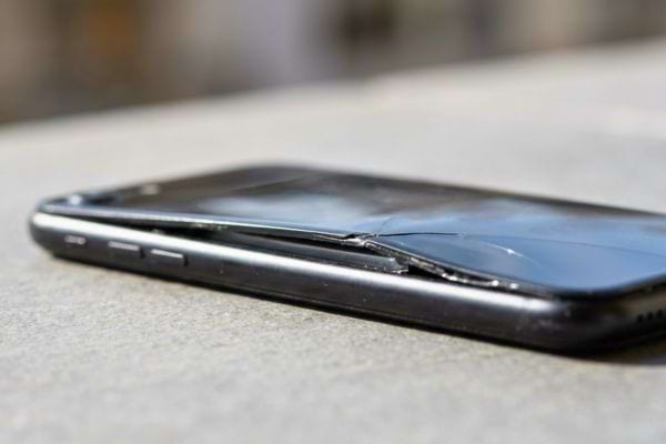 Smartphone avec &eacute;cran fissur&eacute; pos&eacute; sur une surface plane