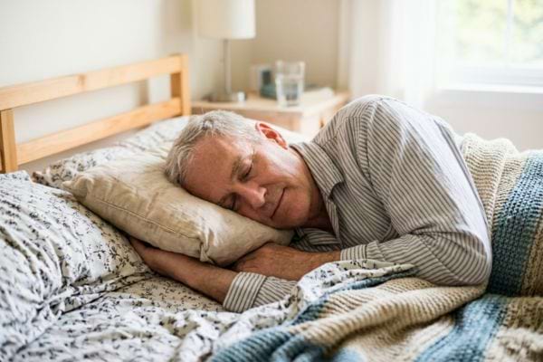 Homme allongé sur le côté dormant paisiblement dans un lit
