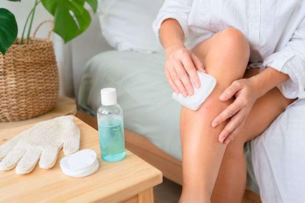 Femme apaisant sa jambe avec un coton après l’épilation.