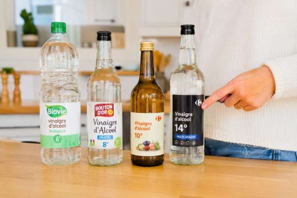 Bouteilles de vinaigre blanc, ménager et d’alcool alignées sur une table.
