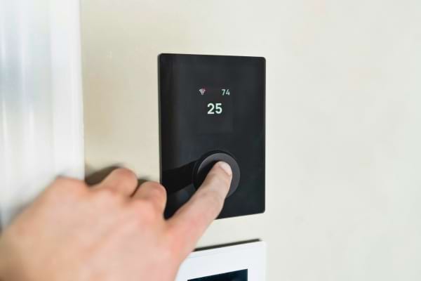 un doigt qui appuie sur un bouton de thermostat