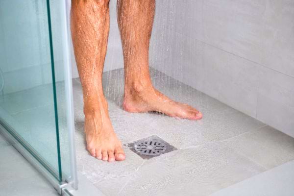 Homme debout sous la douche pr&egrave;s de l&rsquo;&eacute;vacuation.