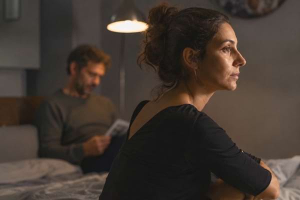 d'une femme de profil, le regard perdu dans le vide, l'air détaché.