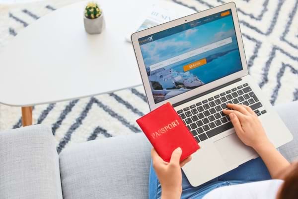 Une personne r&eacute;serve son billet d'avion passeport &agrave; la main