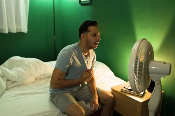 Un homme qui a chaud devant un ventilateur