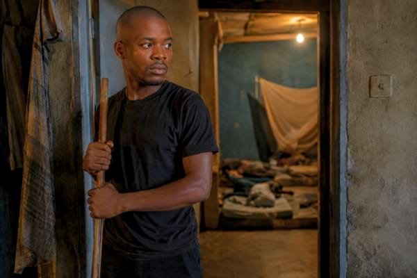 Un jeune homme africain courageux se tenant debout dans la p&eacute;nombre d'un couloir modeste