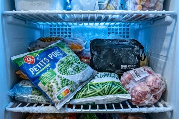 inside a frosty home freezer, showing frozen food bags and ice