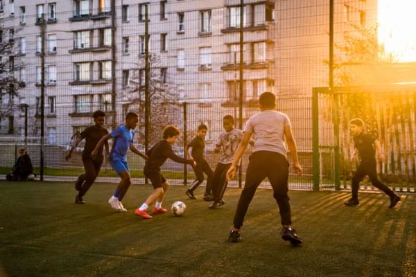 Des jeunes gar&ccedil;ons de diverses origines jouent ensemble avec passion.