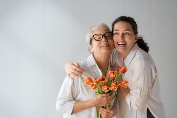 une m&egrave;re &acirc;g&eacute;e et sa fille avec un bouquet de fleurs
